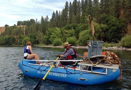 Removing garbage from the Spokane River using rafts.
