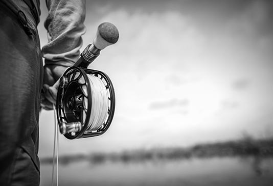 Holding the fly line in your hand.