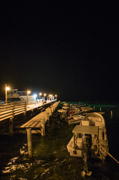 A fleet of sixteen foot Dolphin Skiffs resting at night at Turneffe Flats Lodge.