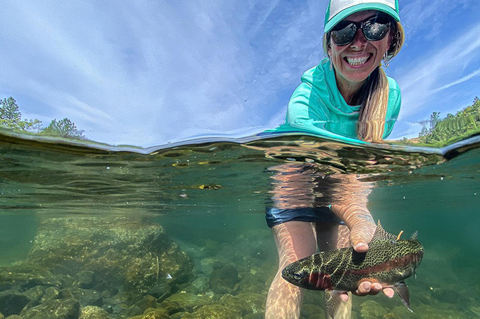 Heather Hodson releasing a vibrant Redband trout during the heat of the summer. Photo Credit: Eric Neufeld